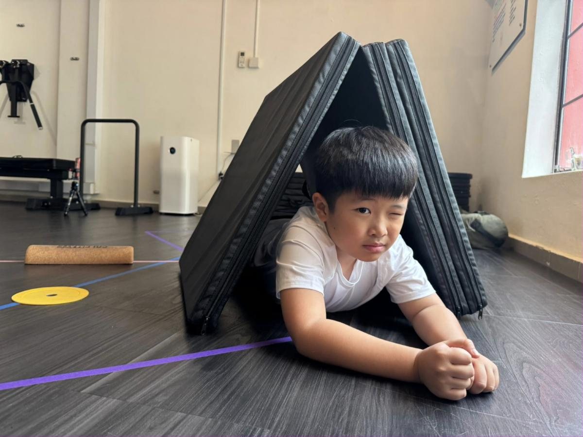 A child crawling out of a mat tunnel during an Uncommon Kids session