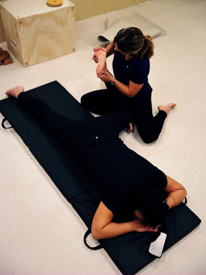 Coach supporting a client through a side-lying hip movement