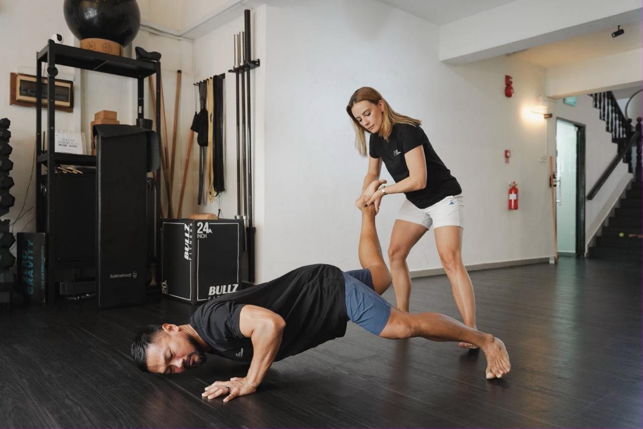 Coach adjusting a client's leg position during a floor exercise